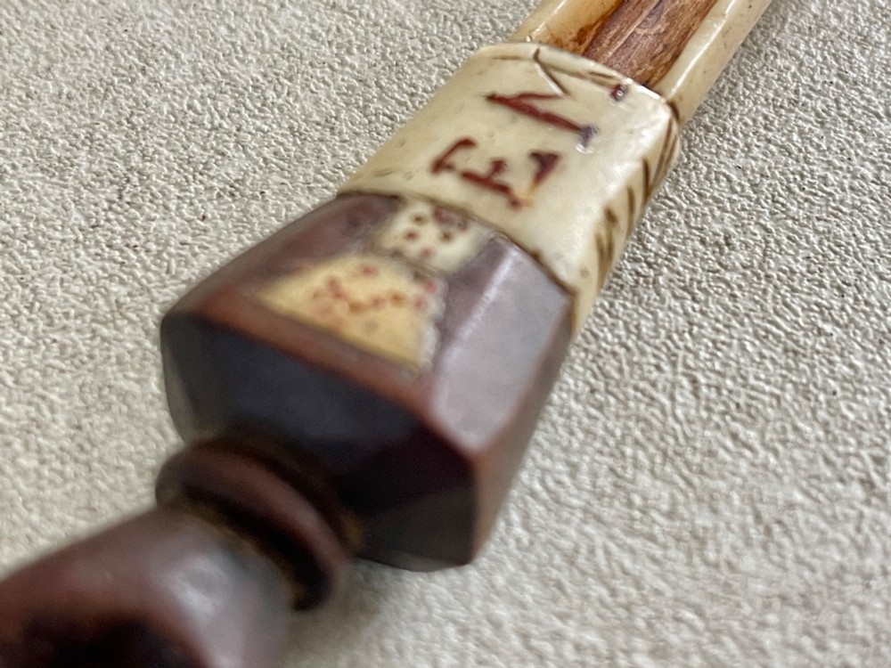 A carved antique bone and wooden apple scoop featuring a terminal in the shape of a clenched fist and carved lettering on the collar. View VII