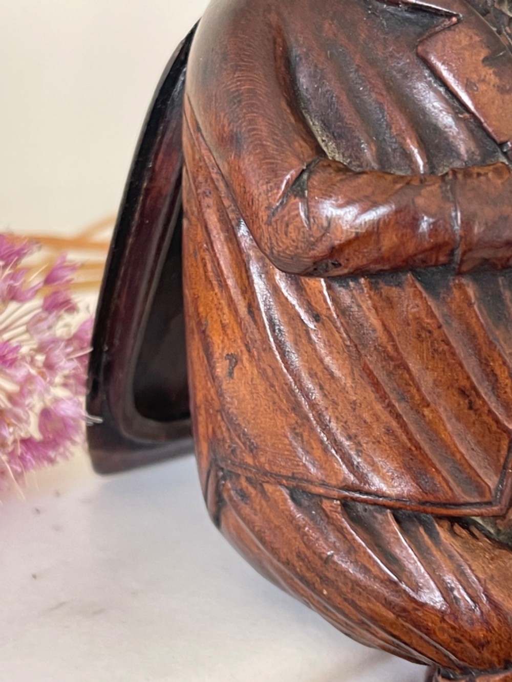 A hand-carved dark wood treen snuff box shaped as a seated man wearing a peaked cap and coat with his legs crossed. View III