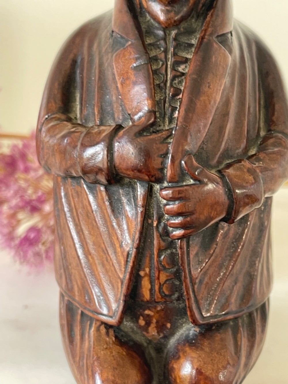 A hand-carved dark wood treen snuff box shaped as a seated man wearing a peaked cap and coat with his legs crossed. View VI