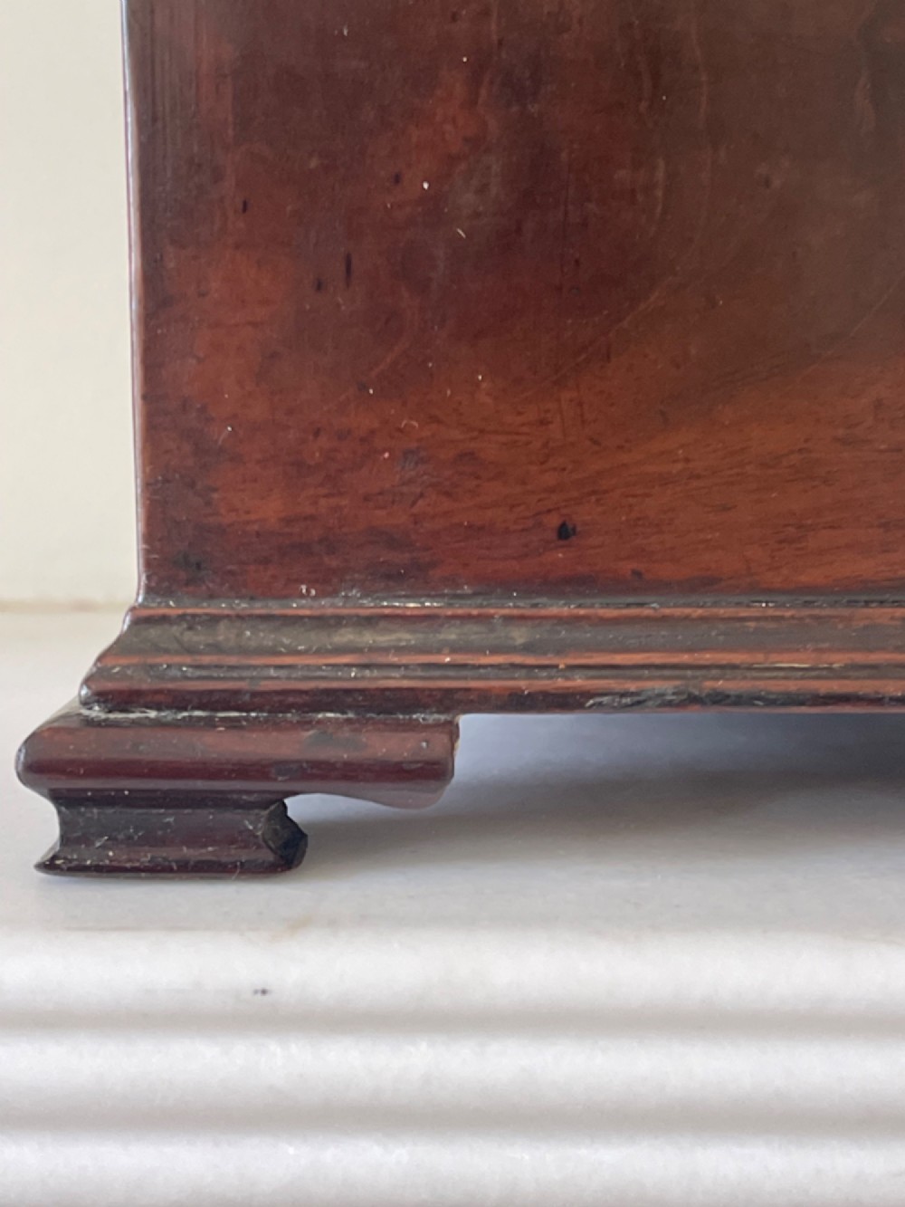 A Georgian dark mahogany tea chest with a stepped lid, brass top handle, ornamental brass escutcheon, and bracket feet. View III