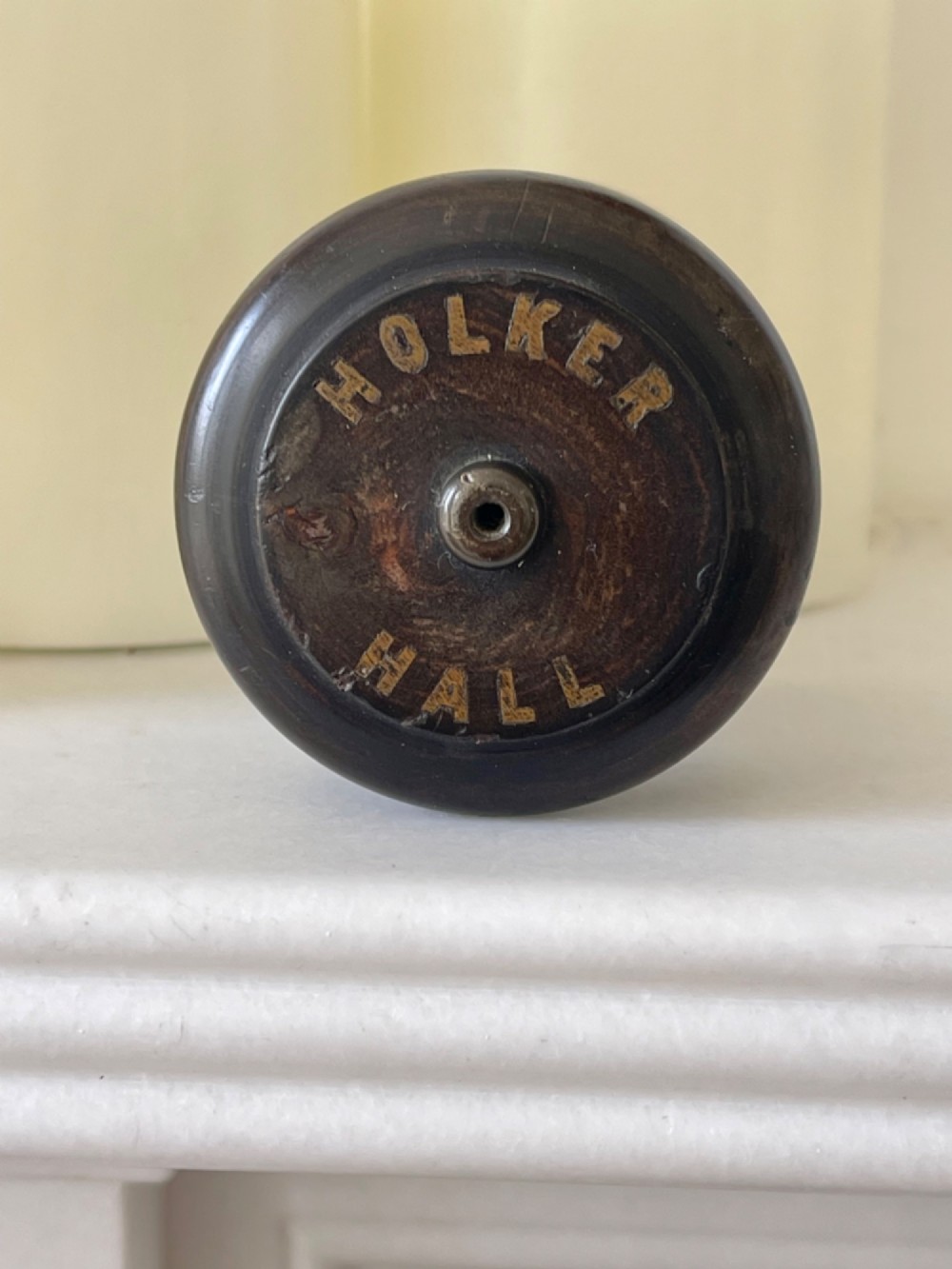 A small turned dark wooden go-to-bed match holder featuring a cylindrical body, a moulded cap, and a match inserted in the centre top. View III