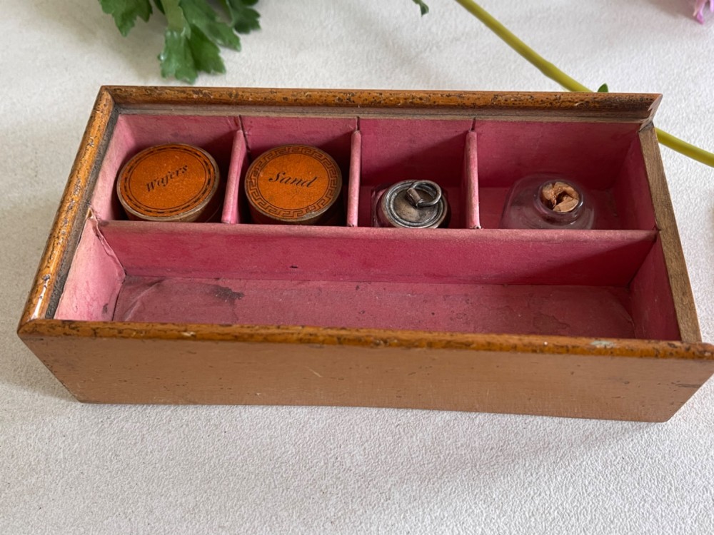 A rectangular wooden box lid featuring a central circular printed vignette of a country house surrounded by geometric green and black borders on an ochre surface. View IV