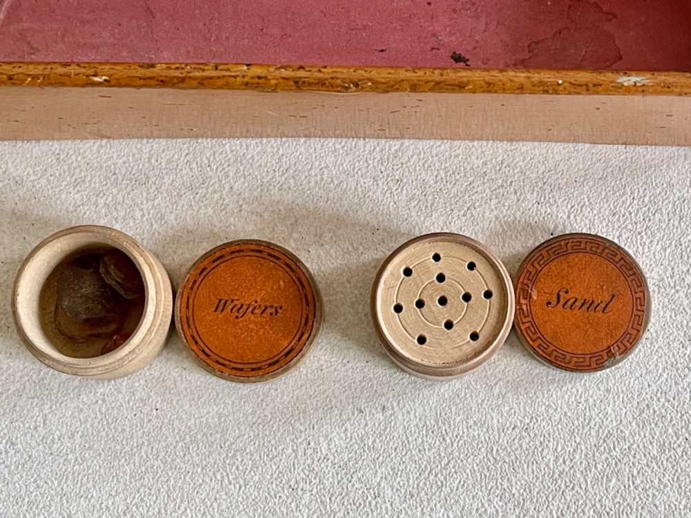 A rectangular wooden box lid featuring a central circular printed vignette of a country house surrounded by geometric green and black borders on an ochre surface. View V