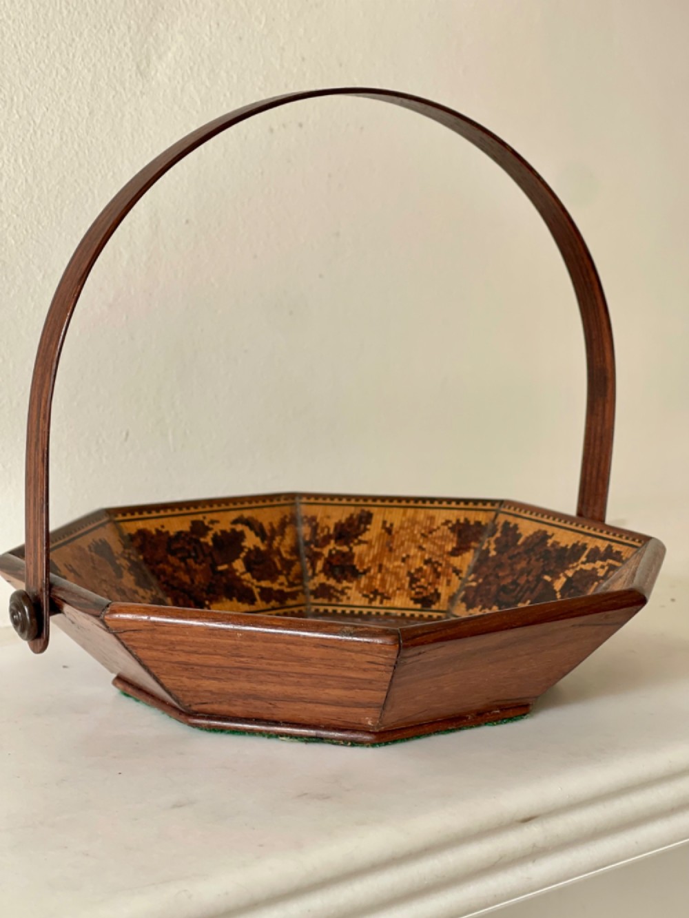 An octagonal Victorian Tunbridge ware wooden sewing basket with a curved overhead handle and floral wood mosaic inlay along the interior panels.