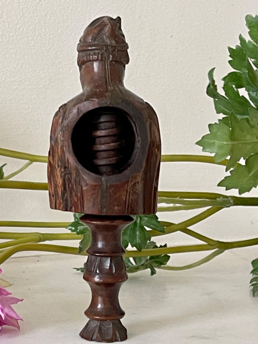 A dark carved wooden treen nutcracker featuring a male bust wearing a cap and jacket atop a turned pedestal handle. View VII