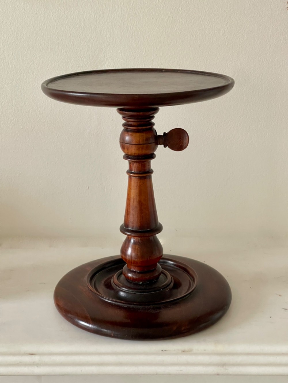 A dark turned mahogany Georgian candle stand featuring a height-adjustment screw mechanism, a dished circular top tray, and a wide circular base. View V