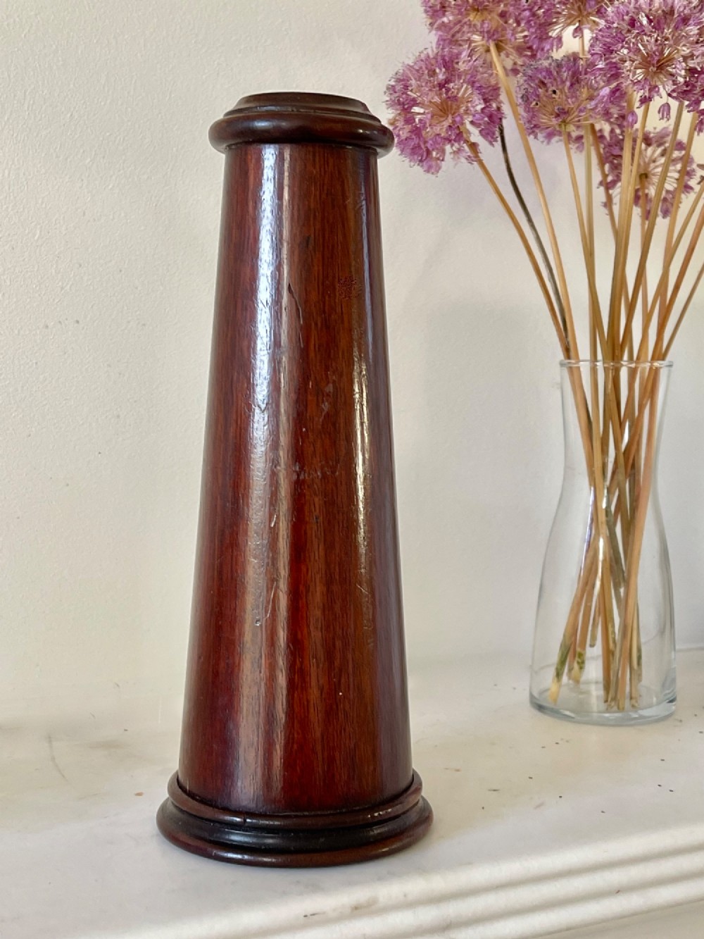 An upright turned dark mahogany wooden kaleidoscope with a tapered conical body and rounded moulded borders.