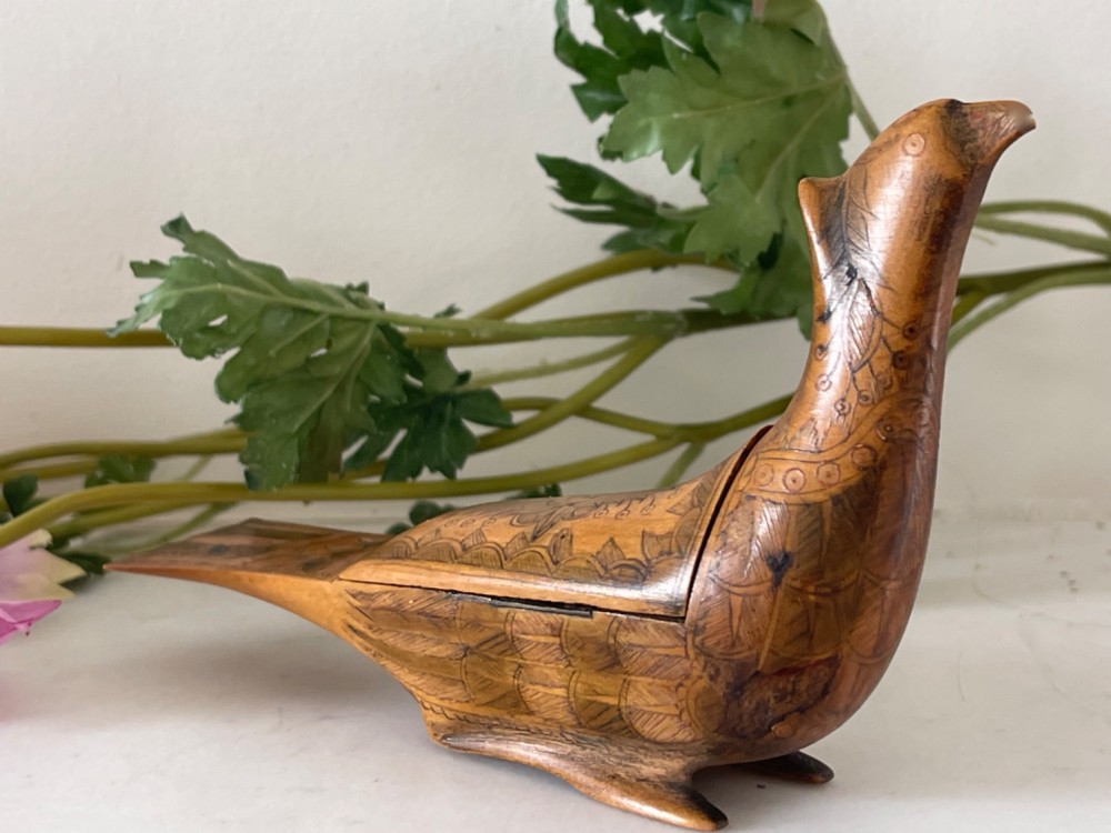 An antique hand-carved wooden snuff box shaped like a bird with incised feather detailing across the body.