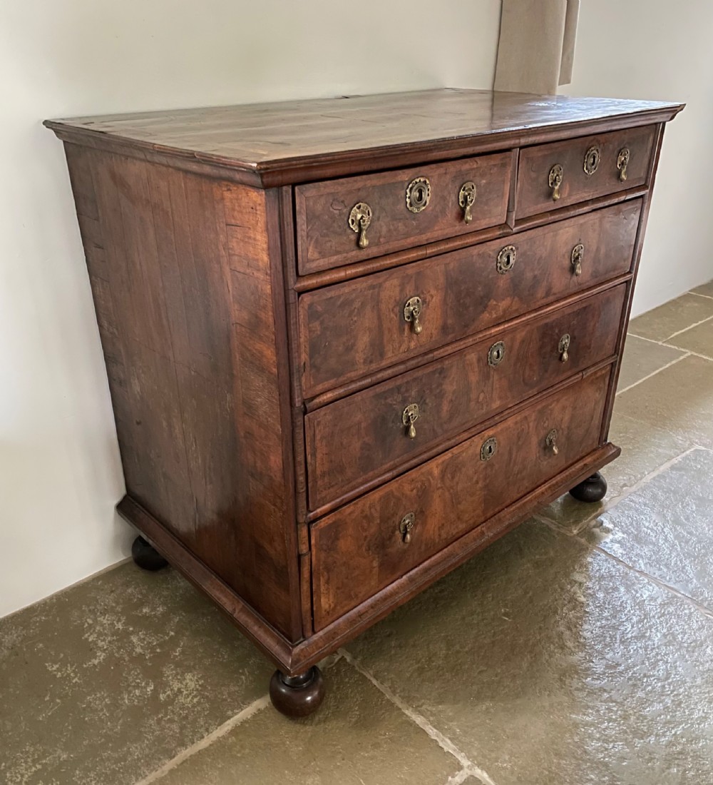 A late 17th-century walnut chest of drawers featuring brass teardrop handles, keyhole escutcheons, crossbanded veneer drawer fronts, and turned bun feet. View III