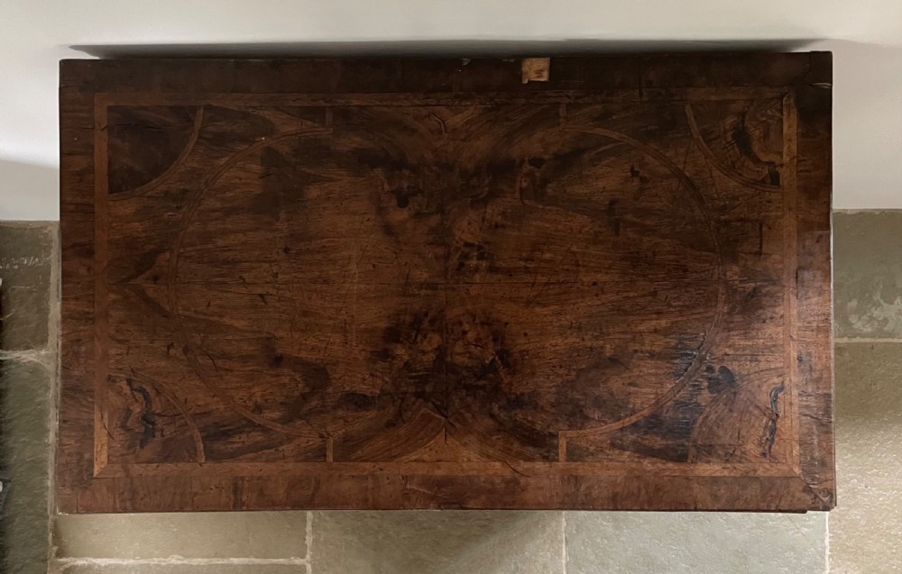A late 17th-century walnut chest of drawers featuring brass teardrop handles, keyhole escutcheons, crossbanded veneer drawer fronts, and turned bun feet. View IV