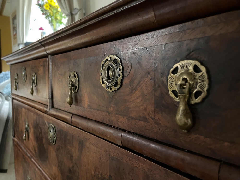 A late 17th-century walnut chest of drawers featuring brass teardrop handles, keyhole escutcheons, crossbanded veneer drawer fronts, and turned bun feet. View XI