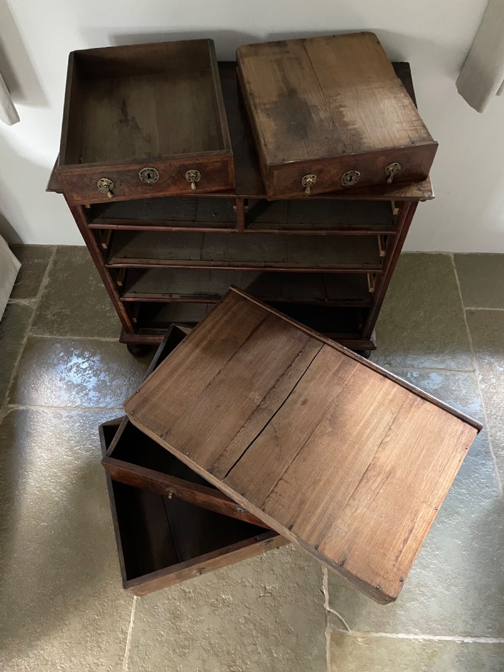 A late 17th-century walnut chest of drawers featuring brass teardrop handles, keyhole escutcheons, crossbanded veneer drawer fronts, and turned bun feet. View XIV