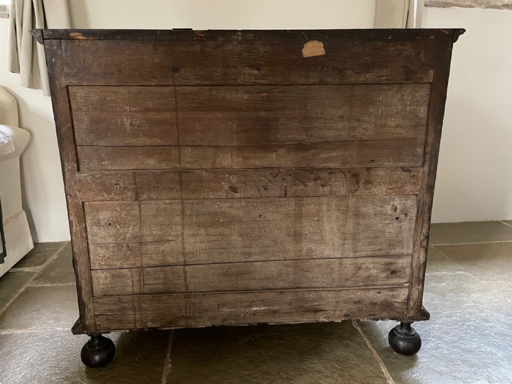 A late 17th-century walnut chest of drawers featuring brass teardrop handles, keyhole escutcheons, crossbanded veneer drawer fronts, and turned bun feet. View XV