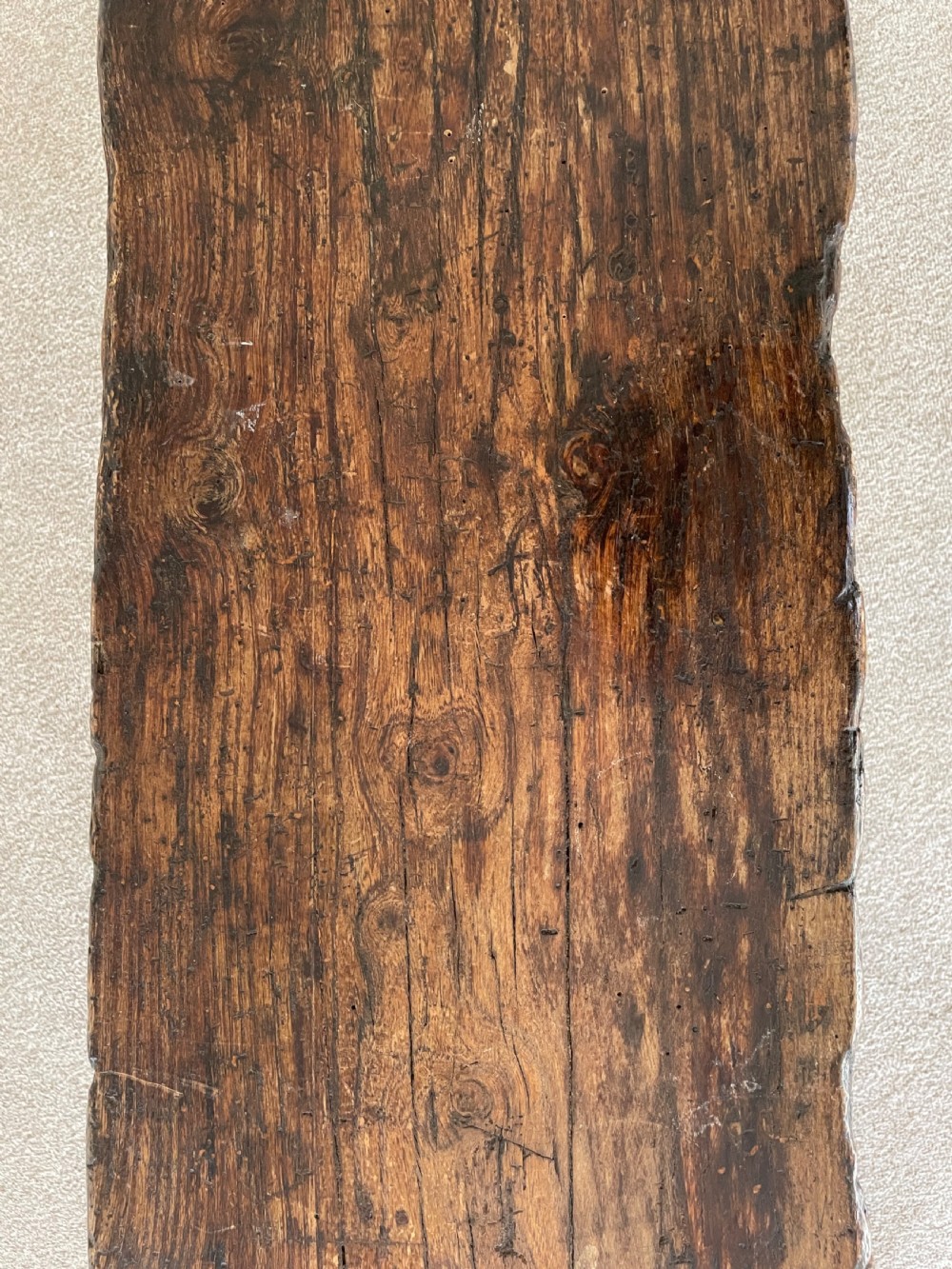 A primitive dark pine bench featuring a thick hand-carved timber seat supported by four splayed round legs. View IX