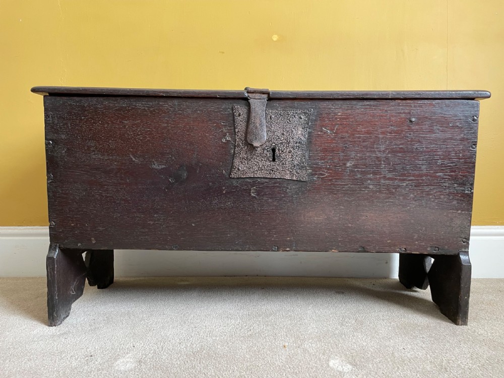 A dark 17th-century Jacobean oak six-plank coffer featuring a hinged lid, iron lockplate, and V-cut slab end supports. View II