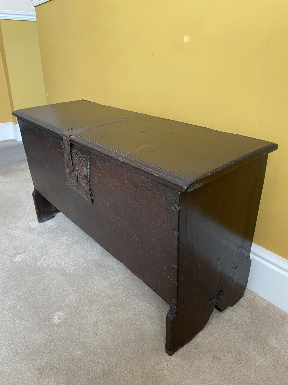 A dark 17th-century Jacobean oak six-plank coffer featuring a hinged lid, iron lockplate, and V-cut slab end supports. View III