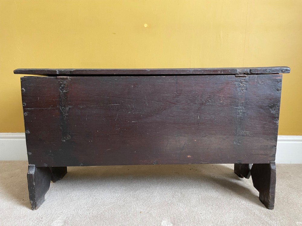 A dark 17th-century Jacobean oak six-plank coffer featuring a hinged lid, iron lockplate, and V-cut slab end supports. View IV