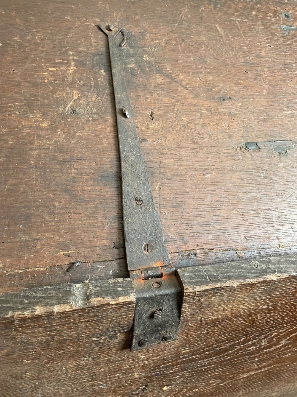 A dark 17th-century Jacobean oak six-plank coffer featuring a hinged lid, iron lockplate, and V-cut slab end supports. View IX