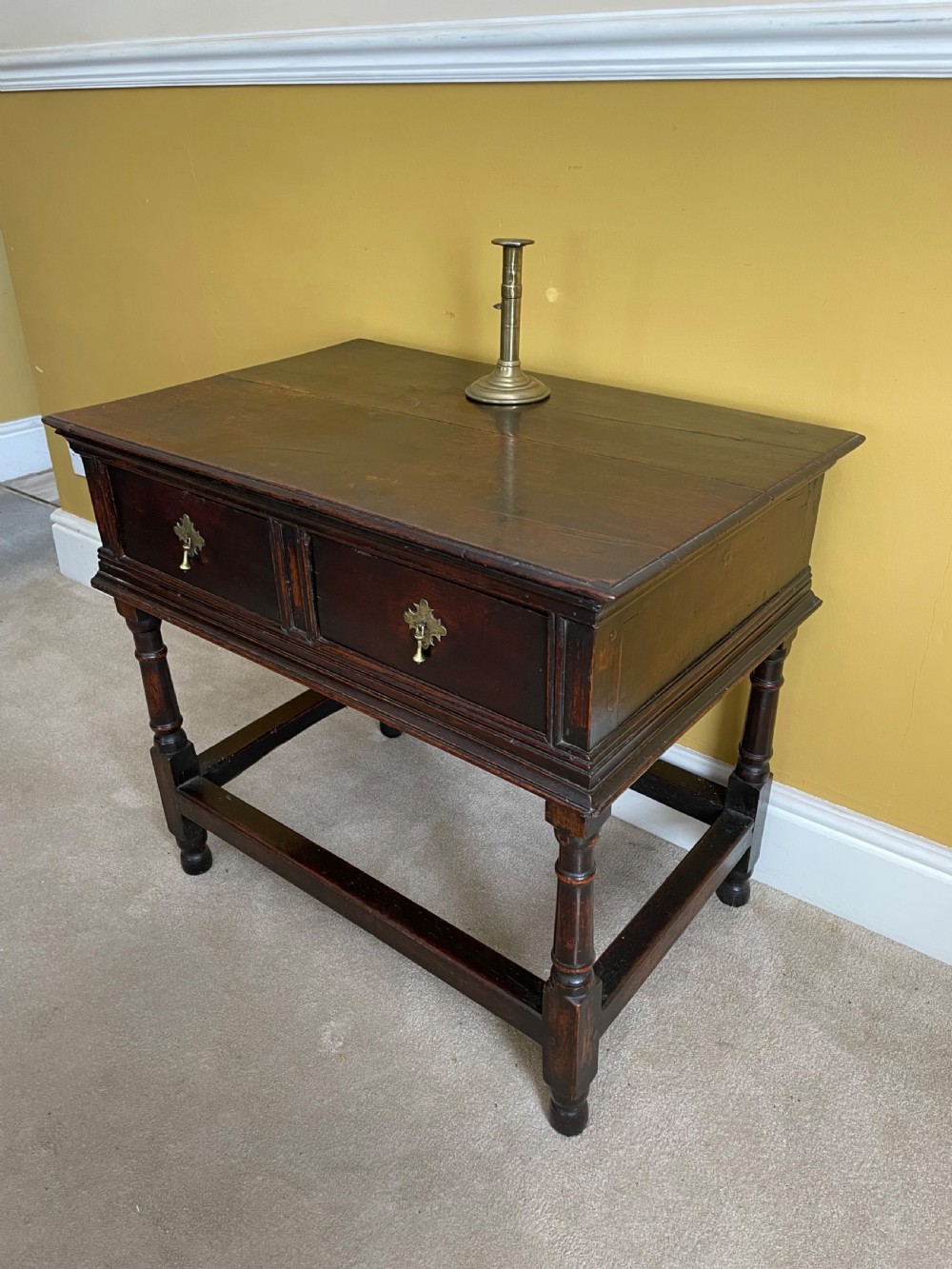 A 17th-century dark oak rent table featuring two frieze drawers with decorative brass handles, supported on turned legs with a rectangular perimeter stretcher. View II