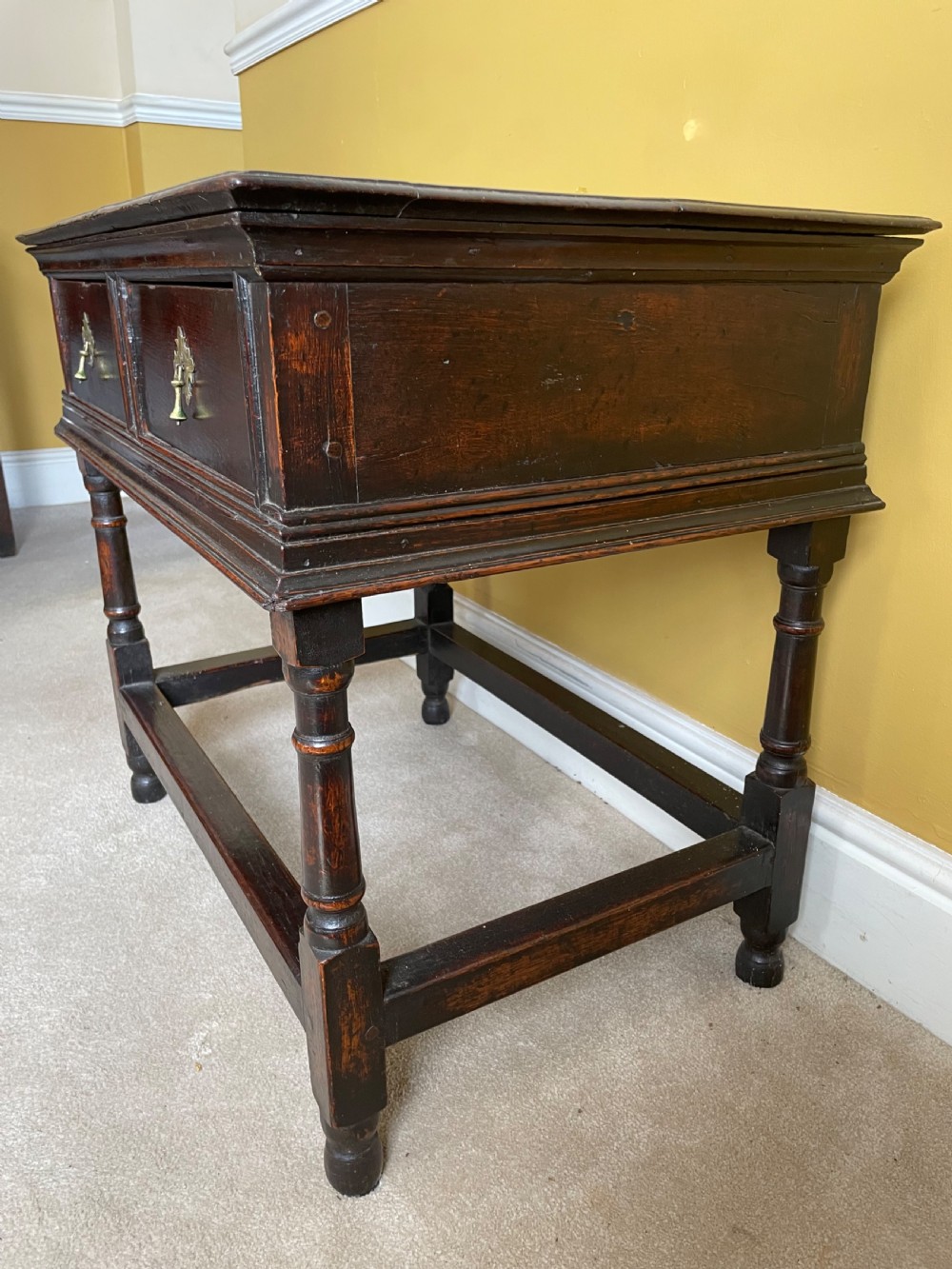 A 17th-century dark oak rent table featuring two frieze drawers with decorative brass handles, supported on turned legs with a rectangular perimeter stretcher. View III