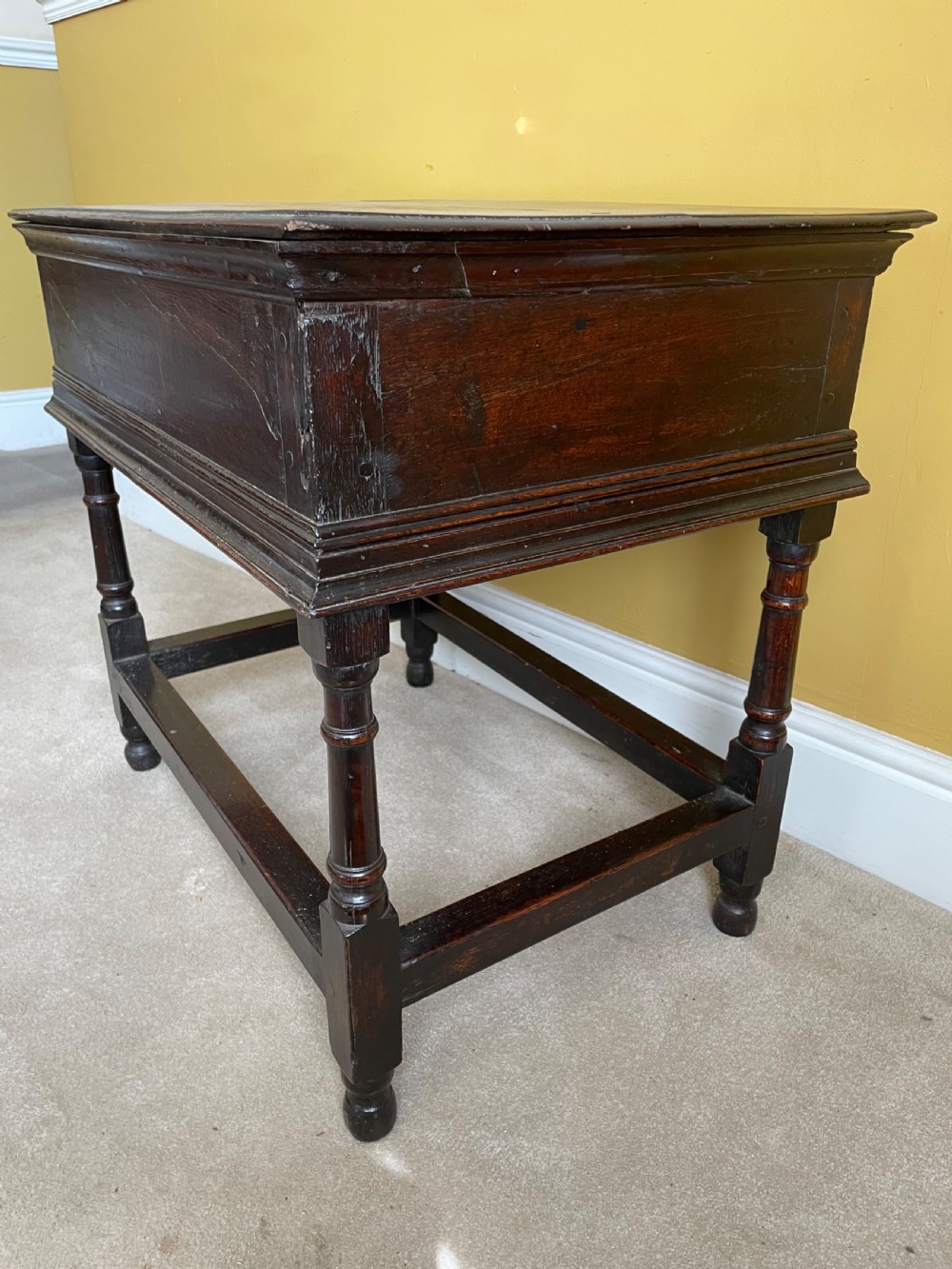 A 17th-century dark oak rent table featuring two frieze drawers with decorative brass handles, supported on turned legs with a rectangular perimeter stretcher. View VI