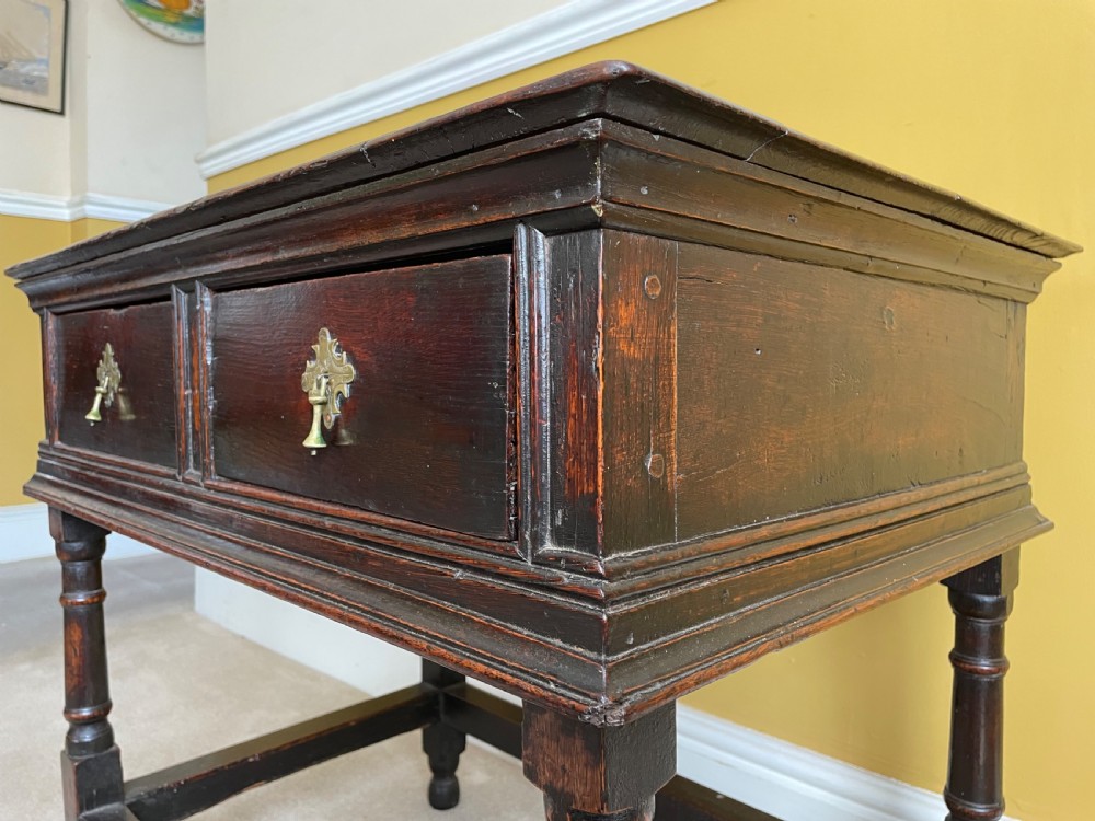 A 17th-century dark oak rent table featuring two frieze drawers with decorative brass handles, supported on turned legs with a rectangular perimeter stretcher. View VIII