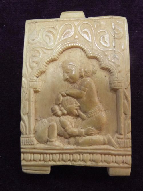 fig 1. A small rectangular cream-coloured carved panel featuring a high-relief figure scene within an arched frame.