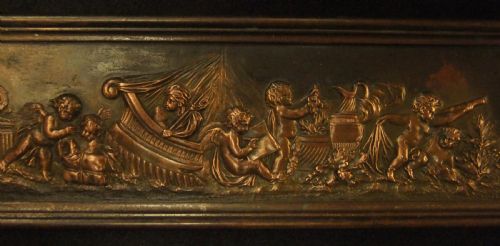 fig 3. A long horizontal dark bronze relief frieze featuring classical cherubs engaged in allegorical scenes set within a slender rectangular frame.