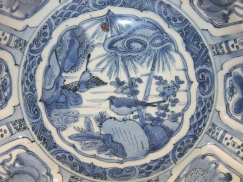 fig 1. A Chinese Wanli Kraak porcelain deep plate decorated in underglaze blue with central birds and plants surrounded by a panelled rim with a scalloped edge.