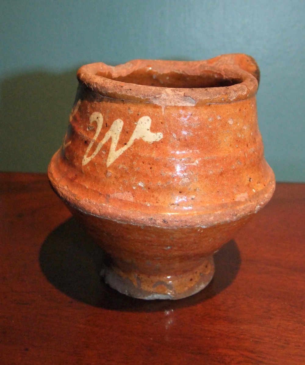 An antique Dutch slipware earthenware jar in terracotta red lead glaze featuring white trailed script lettering and a single handle. View II