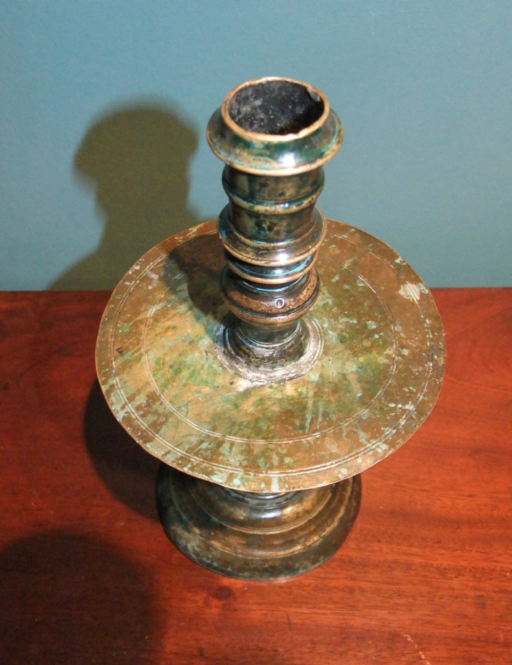 An 18th-century cast brass candlestick featuring a wide central drip collar, turned knopped stem, and a round stepped base. View III