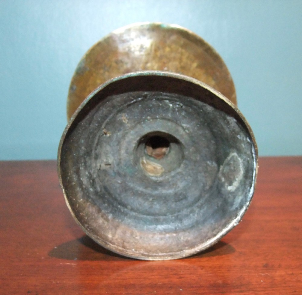 An 18th-century cast brass candlestick featuring a wide central drip collar, turned knopped stem, and a round stepped base. View VI