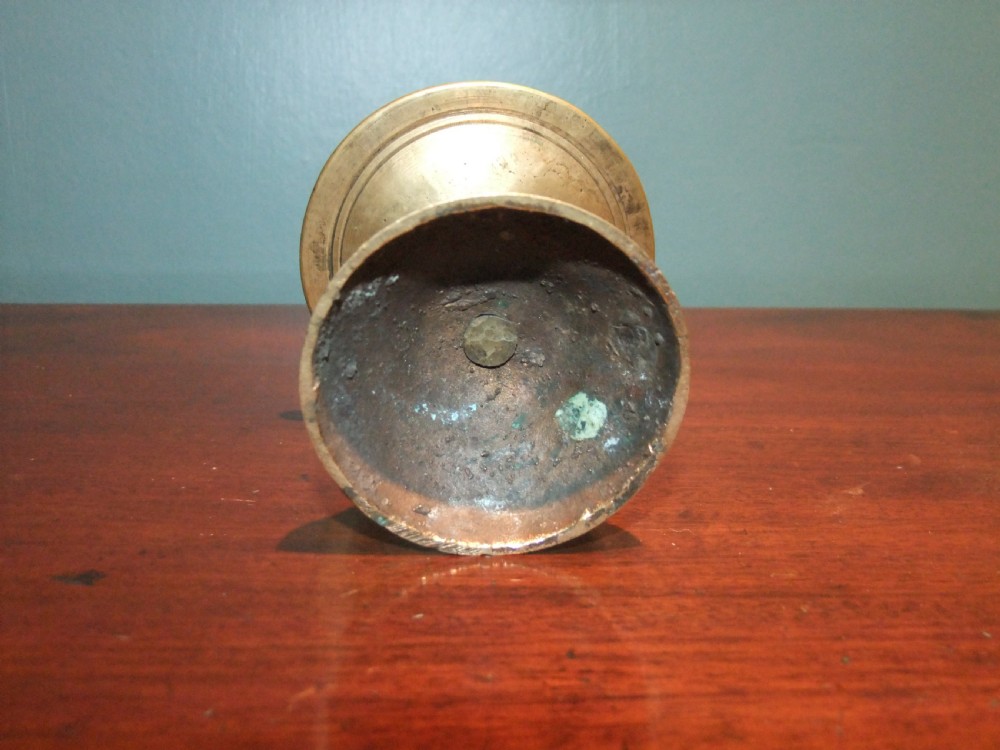 A 17th-century cast brass pricket candlestick featuring a central iron spike, a turned column stem, a wide circular drip tray, and a stepped circular base. View IV