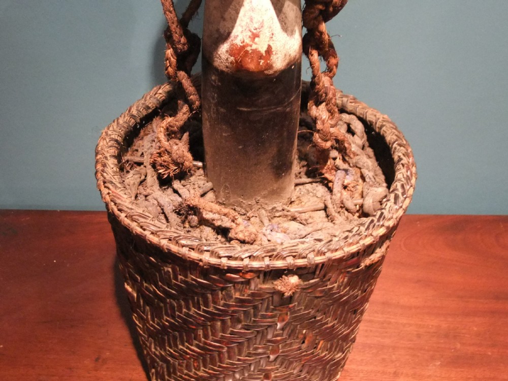 A carved dark wood and white pigment fertility figure mounted inside a woven fibre basket with natural cordage bindings. View VIII