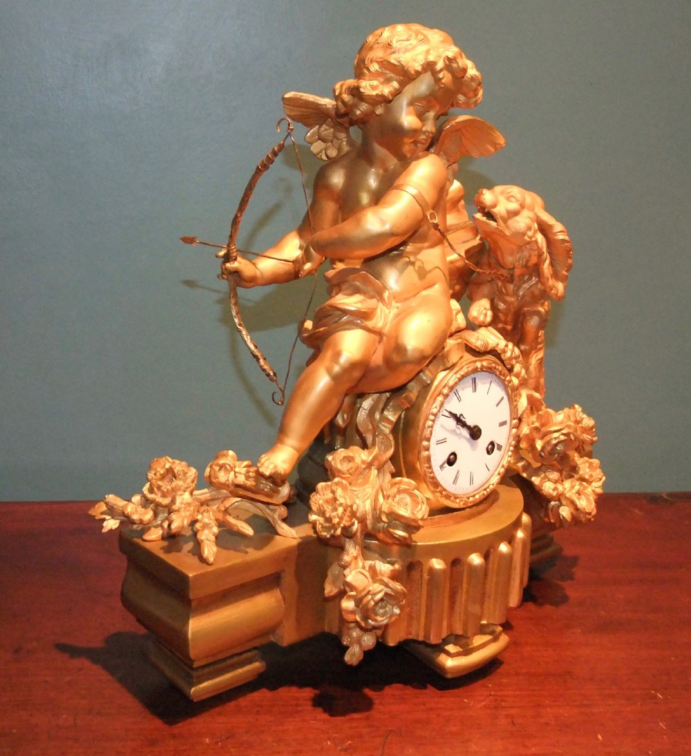 A 19th-century French gilt bronze mantel clock featuring a sculpted putto figure with a bow alongside a dog atop an ornate base. View II