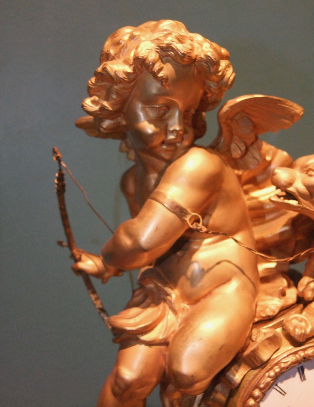 A 19th-century French gilt bronze mantel clock featuring a sculpted putto figure with a bow alongside a dog atop an ornate base. View IV