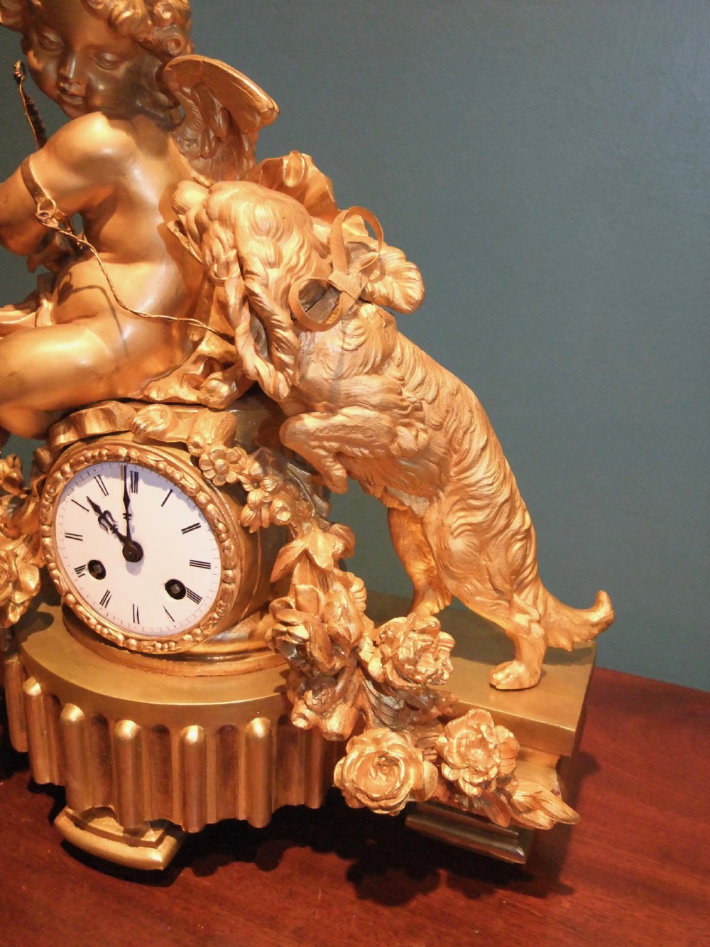 A 19th-century French gilt bronze mantel clock featuring a sculpted putto figure with a bow alongside a dog atop an ornate base. View VII