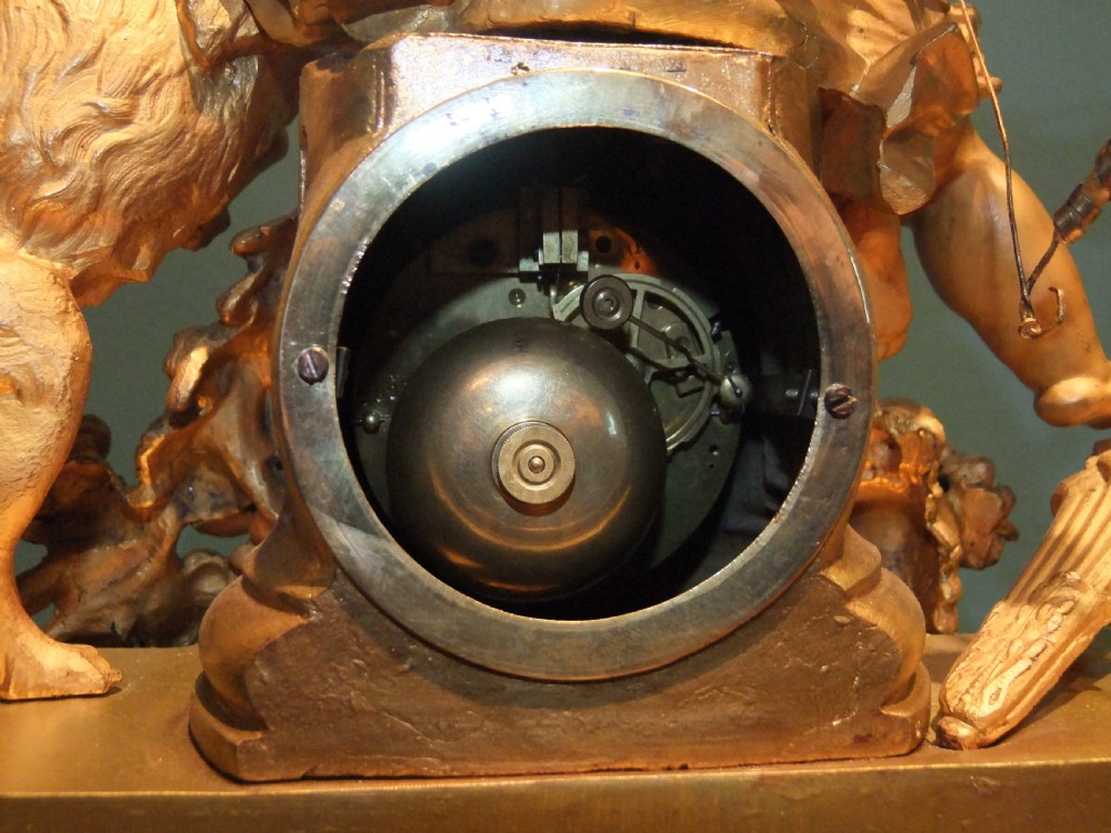 A 19th-century French gilt bronze mantel clock featuring a sculpted putto figure with a bow alongside a dog atop an ornate base. View XIV