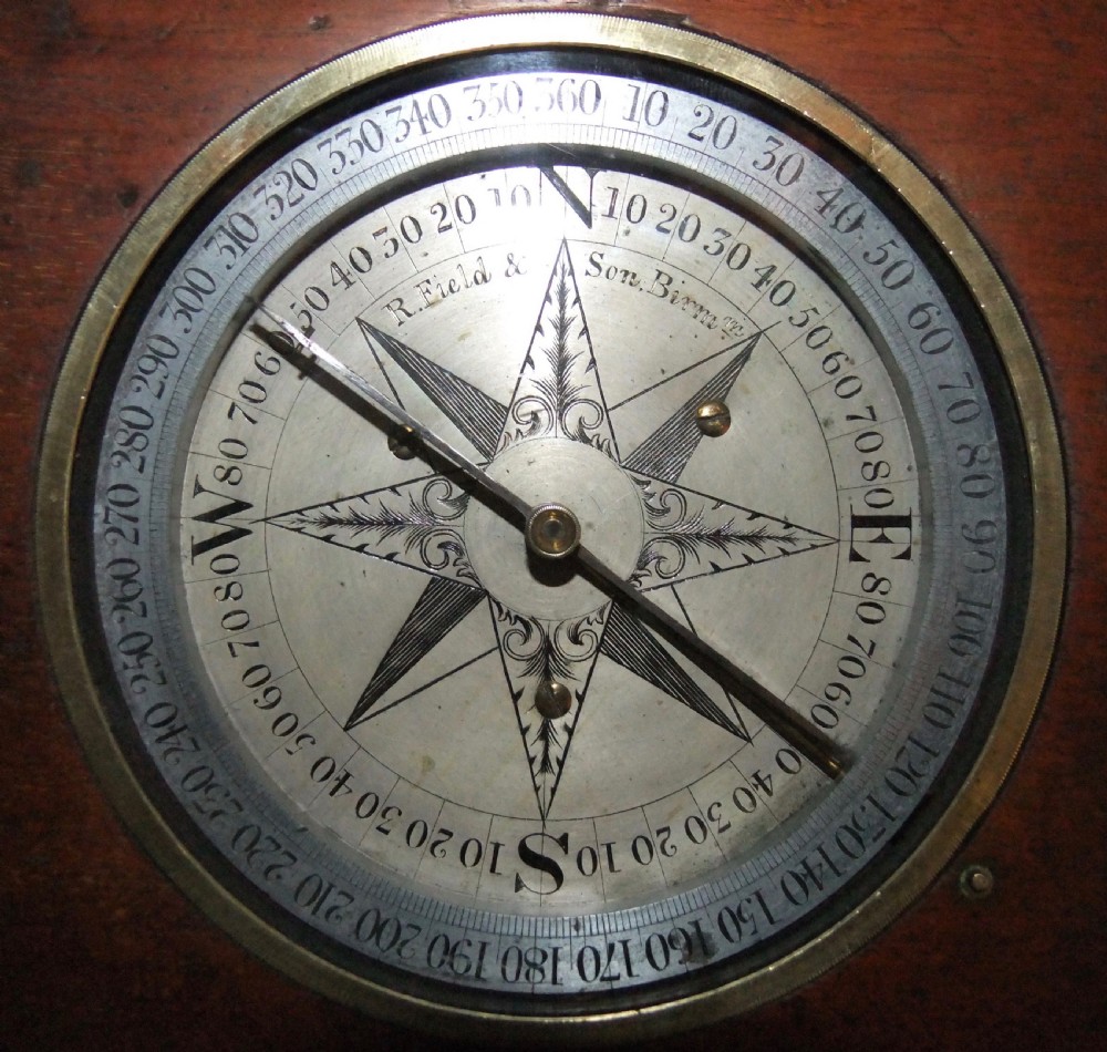 A circular Georgian brass and silvered compass rose with engraved degree markings housed in a square mahogany timber frame.