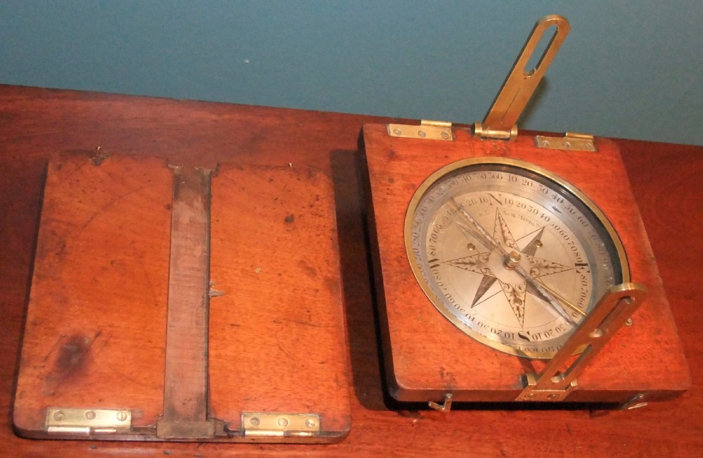 A circular Georgian brass and silvered compass rose with engraved degree markings housed in a square mahogany timber frame. View V