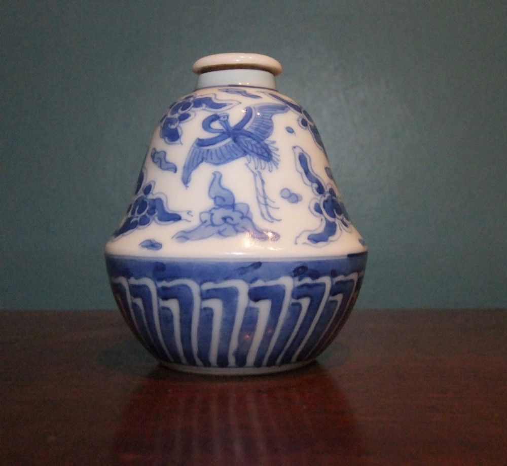 A small bell-shaped Chinese blue and white porcelain lidded bottle decorated with hand-painted flying cranes and cloud motifs. View VII