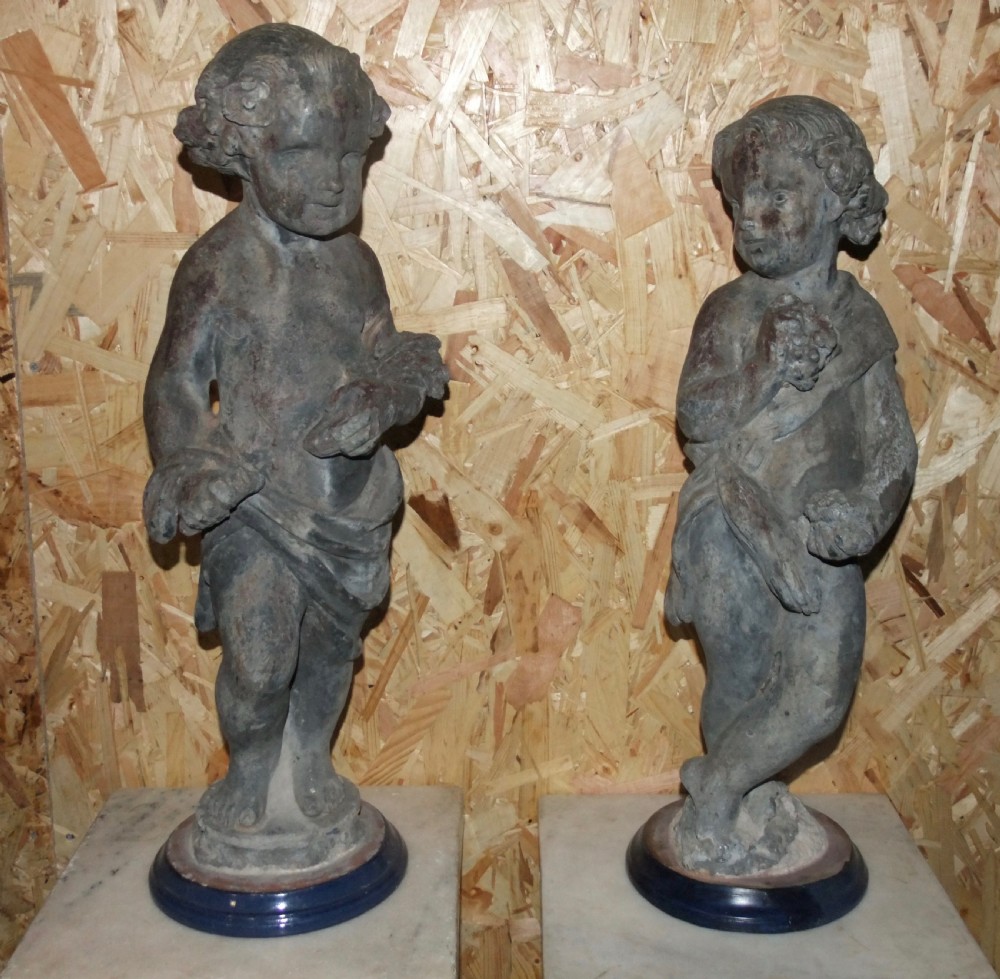 A pair of eighteenth-century Georgian cast lead garden statues depicting standing putti draped in classical fabric.