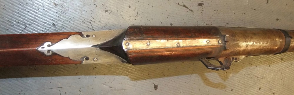 An early 18th-century Indian Toradar matchlock musket with an elongated dark wood stock, a long steel barrel, and metal lock plates. View V