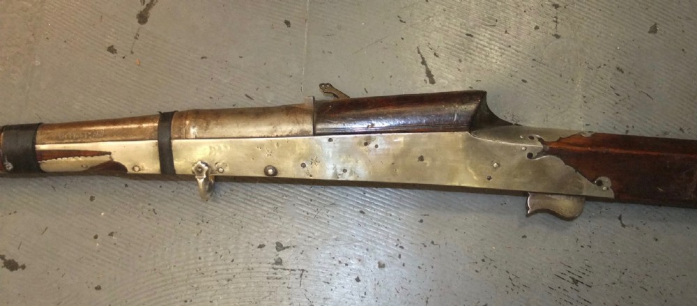 An early 18th-century Indian Toradar matchlock musket with an elongated dark wood stock, a long steel barrel, and metal lock plates. View IX