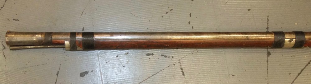 An early 18th-century Indian Toradar matchlock musket with an elongated dark wood stock, a long steel barrel, and metal lock plates. View XVI