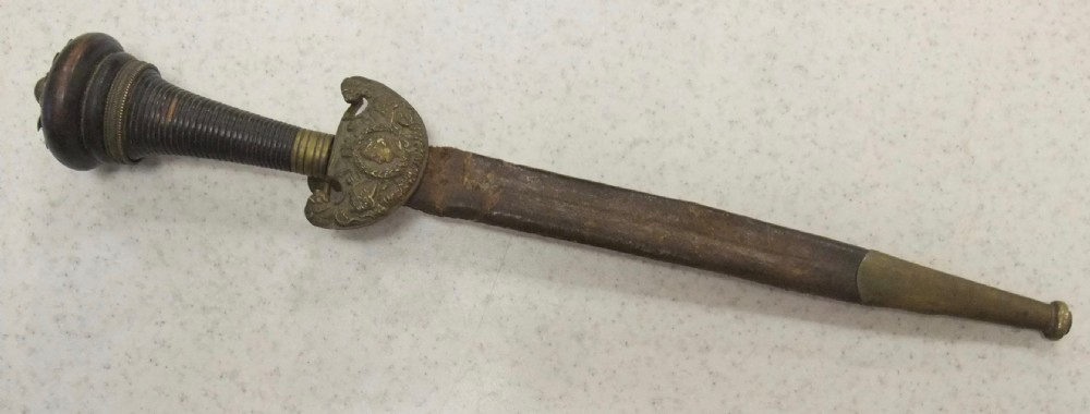 An antique French Napoleonic naval dagger with a tapered steel blade, ornate brass guard, turned dark grip, and leather scabbard. View II