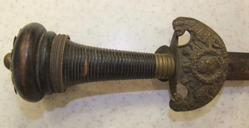 An antique French Napoleonic naval dagger with a tapered steel blade, ornate brass guard, turned dark grip, and leather scabbard. View III