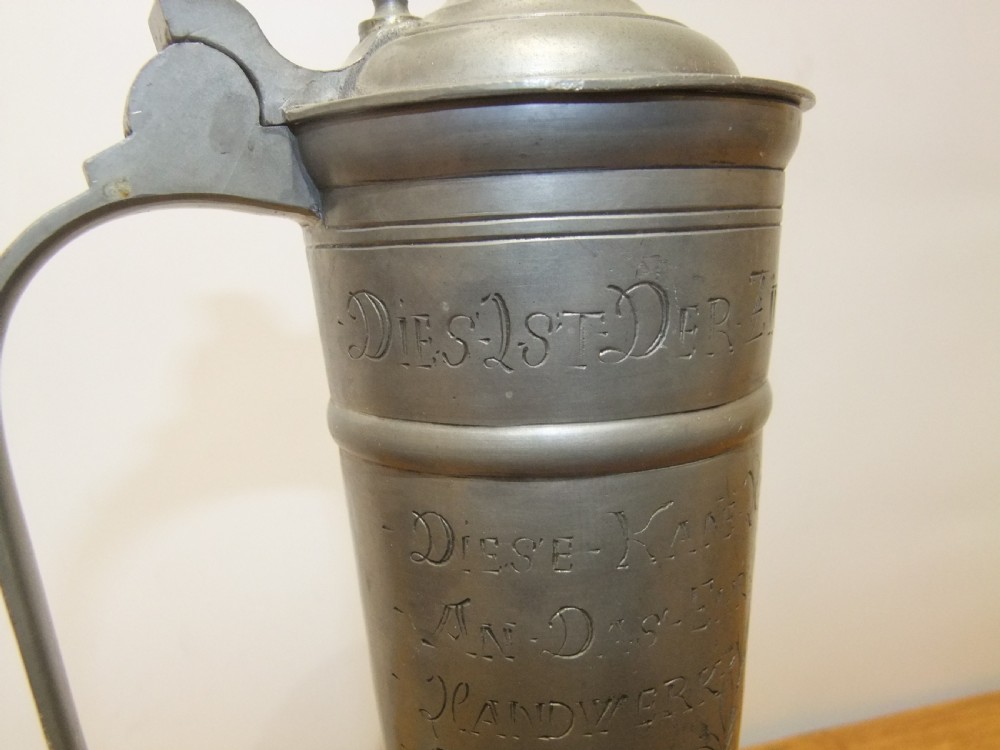 A tall 19th-century German lidded pewter tankard featuring hand-engraved Masonic iconography, floral sprigs, German text, a hinged lid with finial, and a flared pedestal base. View VIII