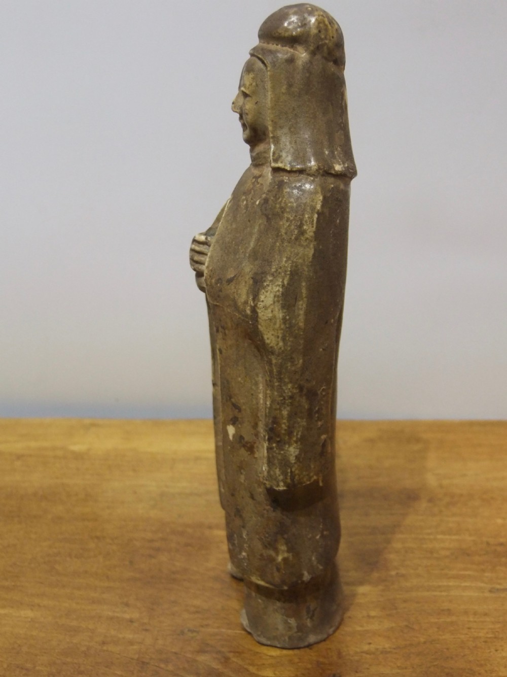 A standing Sui Dynasty earthenware tomb attendant figure featuring draped robes, a tall headpiece, folded hands, and traces of original surface pigments. View II