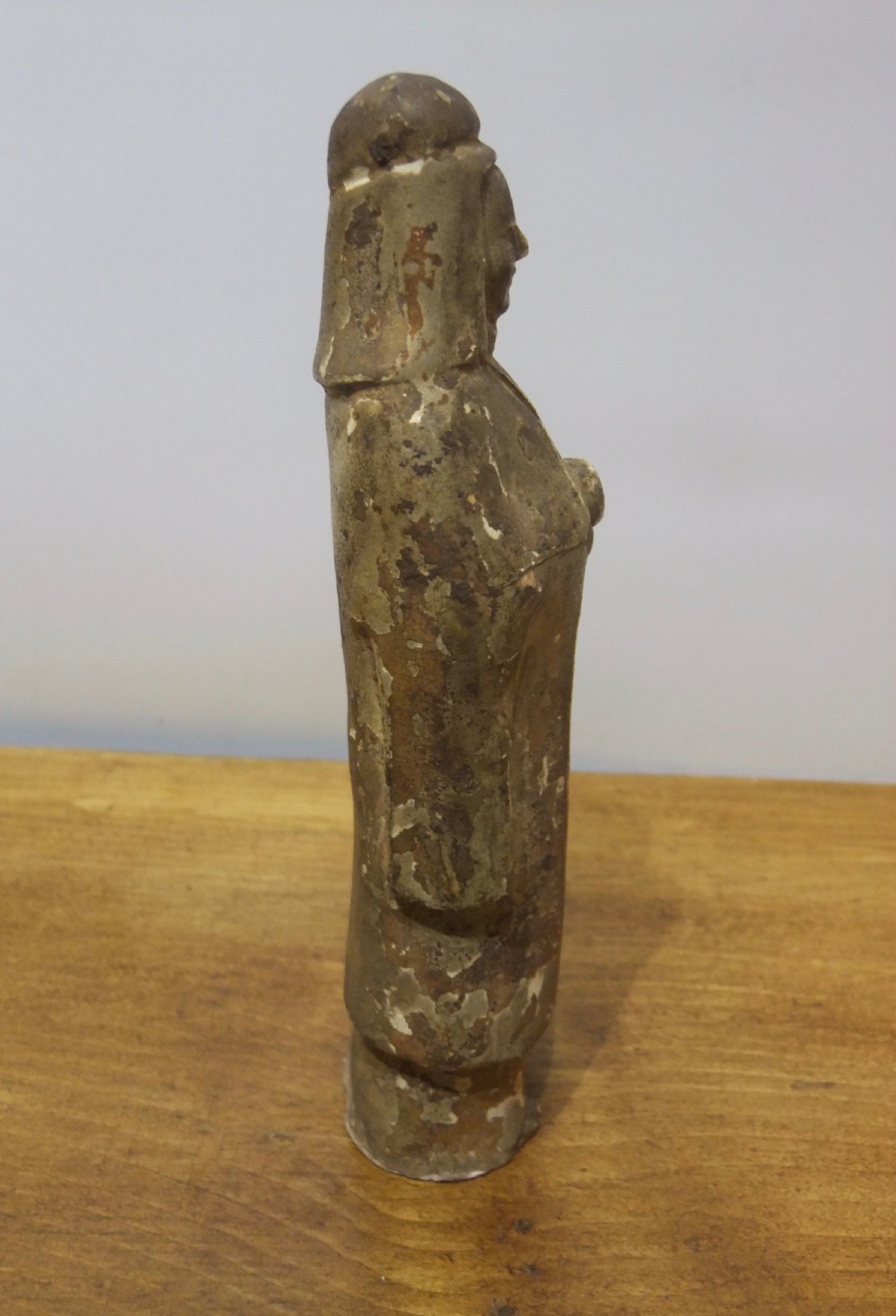 A standing Sui Dynasty earthenware tomb attendant figure featuring draped robes, a tall headpiece, folded hands, and traces of original surface pigments. View IV
